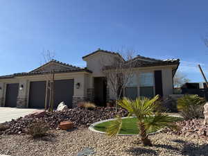 View of front of home with a tile roof, stucco siding, concrete driveway, a garage, and stone siding