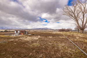 View of yard with a rural view, a mountain view, and fence