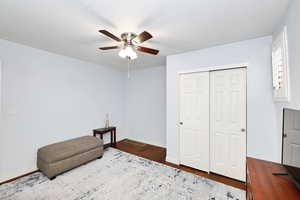 Sitting room with dark wood-style floors, a textured ceiling, a ceiling fan, and baseboards