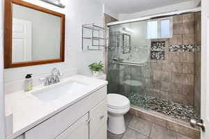 Bathroom with a stall shower, tile patterned flooring, vanity, and toilet