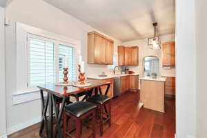 Kitchen featuring dark wood-style flooring, light countertops, hanging light fixtures, a sink, and dishwasher