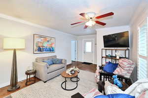 Living area with a textured ceiling, wood finished floors, and crown molding