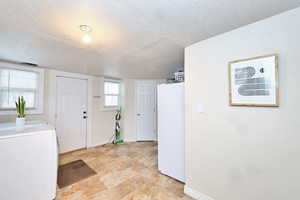 Foyer entrance with a textured ceiling, washer / clothes dryer, and baseboards