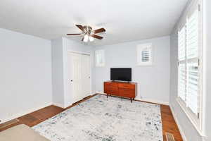 Interior space with ceiling fan, a textured ceiling, wood finished floors, visible vents, and baseboards