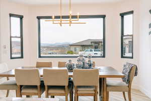 Dining room featuring a notable chandelier, light wood-style floors, baseboards, and a healthy amount of sunlight