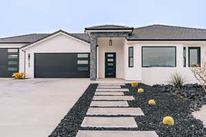 View of front of property with a garage, concrete driveway, a tile roof, and stucco siding