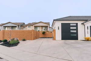 View of front of house featuring concrete driveway, fence, and stucco siding