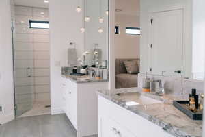 Full bathroom featuring tasteful backsplash, a stall shower, two vanities, and a sink