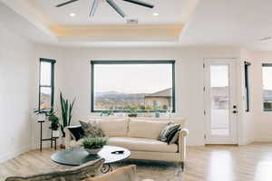 Living area with a mountain view, a tray ceiling, light wood-type flooring, and visible vents