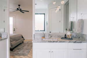 Bathroom featuring ceiling fan, wood finished floors, vanity, and connected bathroom