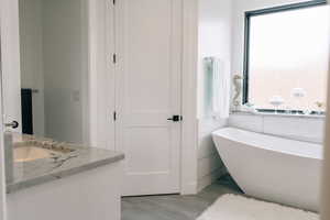 Full bathroom featuring a soaking tub and vanity