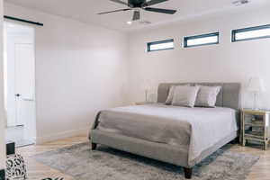 Bedroom featuring light wood-style floors, a barn door, visible vents, and baseboards