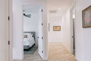 Corridor with light wood-type flooring, baseboards, visible vents, and recessed lighting