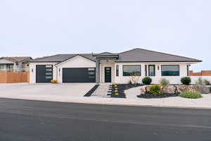 View of front of house with a garage, driveway, a tiled roof, fence, and stucco siding