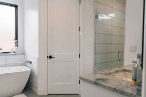 Full bath with a stall shower, a freestanding tub, vanity, and tile walls