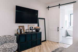 Interior space featuring light wood-style floors, ensuite bath, and a barn door