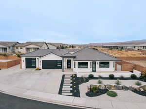 View of front of house with an attached garage, driveway, fence, and stucco siding