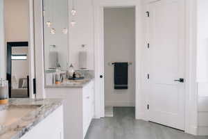 Full bathroom with two vanities, a sink, and baseboards