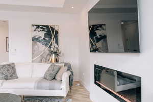 Living room featuring baseboards, a glass covered fireplace, light wood-style flooring, and recessed lighting