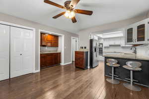 Kitchen featuring dark wood-type flooring, a sink, white cabinets, appliances with stainless steel finishes, and glass insert cabinets