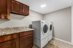 Clothes washing area featuring cabinet space, independent washer and dryer, baseboards, and light tile patterned floors