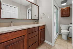 Primary Bedroom's Bathroom with tile patterned flooring, a sink, toilet, and double vanity