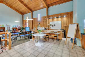 Kitchen with wooden walls, high vaulted ceiling, pendant lighting, wood ceiling, and beamed ceiling