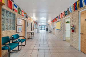 Interior space featuring light tile patterned flooring, brick wall, and a textured ceiling