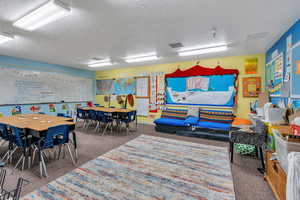 Playroom featuring dark colored carpet and a textured ceiling