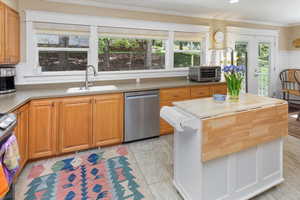 Kitchen featuring ornamental molding, a toaster, a kitchen island, dishwasher, and a sink