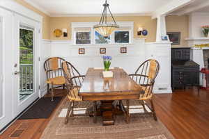 Dining area featuring ornamental molding, dark wood-style floors, and a wainscoted wall