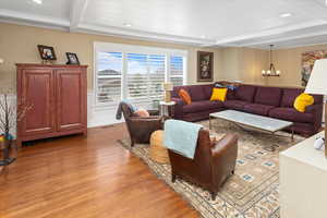 Living room with an inviting chandelier, ornamental molding, recessed lighting, light wood-style flooring, and beam ceiling