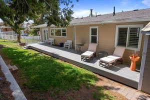 Rear view of property featuring fence, a  deck, and a lawn