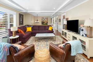 Living area with a chandelier, recessed lighting, wainscoting, beamed ceiling, and wood finished floors