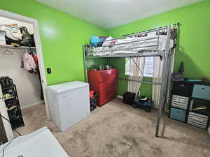 Bedroom with fridge, a closet, and light colored carpet