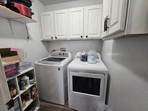 Washroom with dark wood-style floors, separate washer and dryer, and cabinet space