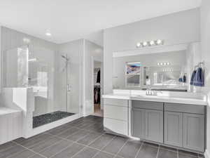 Bathroom featuring a spacious closet, a walk in shower, vanity, and tile floors