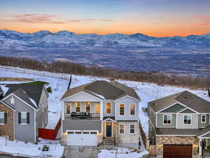 View of front of home featuring an attached garage, a balcony, a mountain and valley view, stone and clapboard and siding