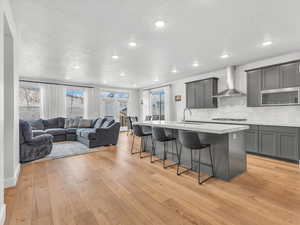 Kitchen with breakfast bar area, open floor plan, white countertops, and a center island with sink