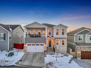 View of front of property with an attached garage, stone and clapboard siding, and a balcony