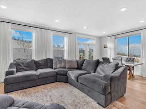 Living room with light wood LVP floors, and recessed lighting