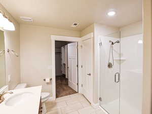 Bathroom featuring vanity, toilet, a textured ceiling, and walk in shower