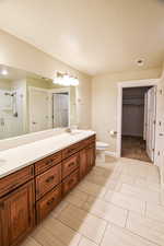 Bathroom with a textured ceiling, toilet, vanity, and a shower with door