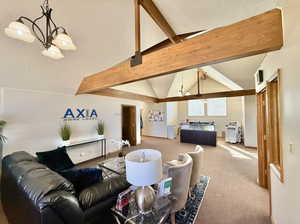 Carpeted upstairs office lobby with lofted ceiling with beams, and a chandelier