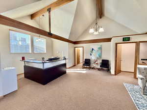 Carpeted upstairs office lobby with lofted ceiling with beams, and a chandelier