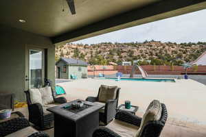 View of patio with a fenced in pool, an outbuilding, an outdoor fire pit, a mountain view, and fence