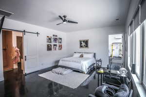 Bedroom featuring a barn door, a ceiling fan, visible vents, and baseboards