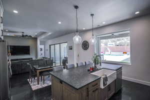 Kitchen featuring appliances with stainless steel finishes, open floor plan, a kitchen island with sink, pendant lighting, and a sink