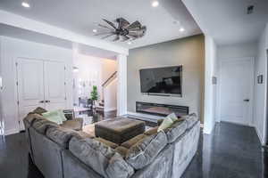 Living area with baseboards, visible vents, a glass covered fireplace, stairs, and recessed lighting