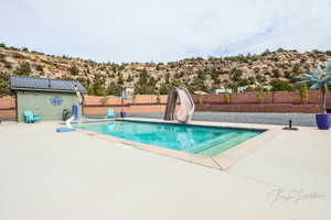 View of pool with a water slide, a patio area, a fenced backyard, and a fenced in pool